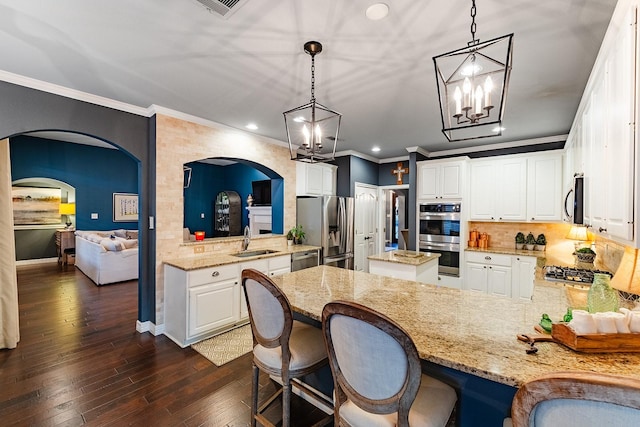 kitchen featuring decorative light fixtures, stainless steel appliances, sink, kitchen peninsula, and a breakfast bar