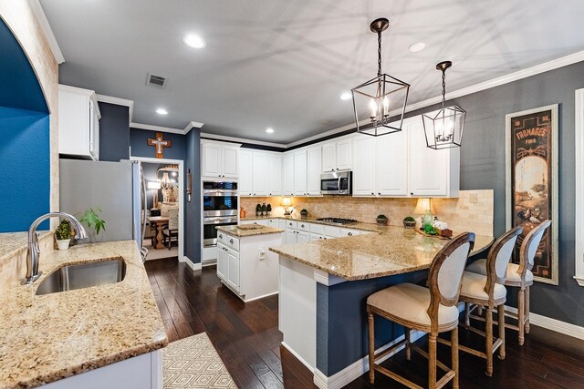 kitchen featuring appliances with stainless steel finishes, white cabinetry, sink, hanging light fixtures, and kitchen peninsula