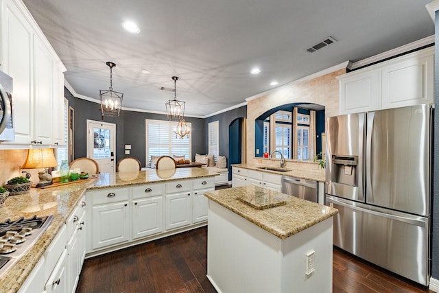 kitchen with kitchen peninsula, decorative light fixtures, sink, white cabinets, and stainless steel appliances