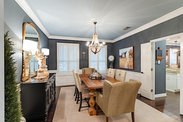 dining space featuring dark hardwood / wood-style flooring, crown molding, and a chandelier