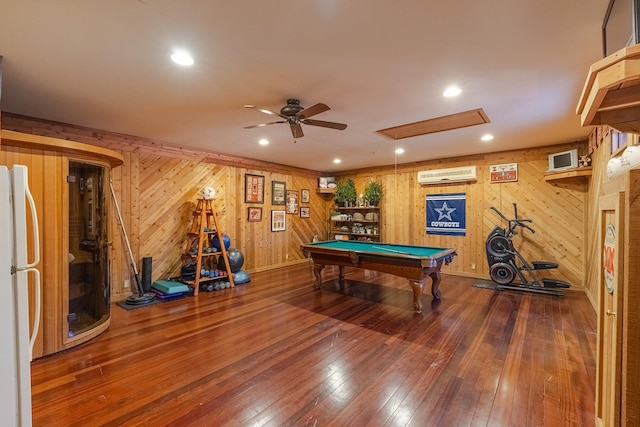 recreation room with wood-type flooring, pool table, wood walls, a wall mounted AC, and ceiling fan