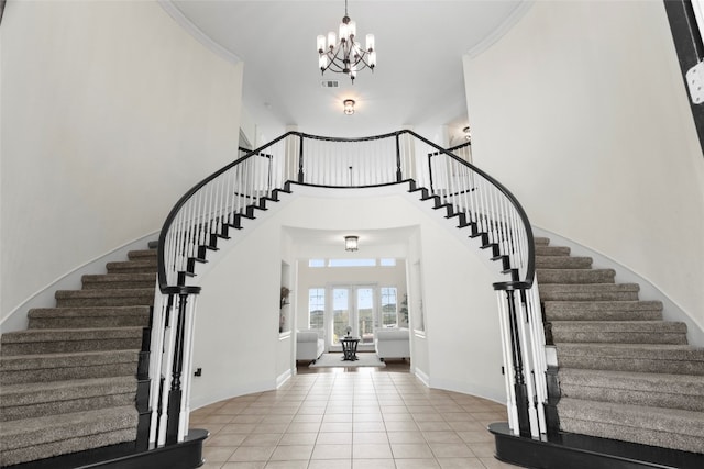 tiled entryway with ornamental molding, french doors, and a chandelier