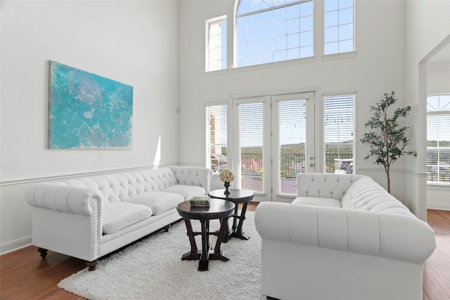 living room with wood-type flooring, a wealth of natural light, and a high ceiling