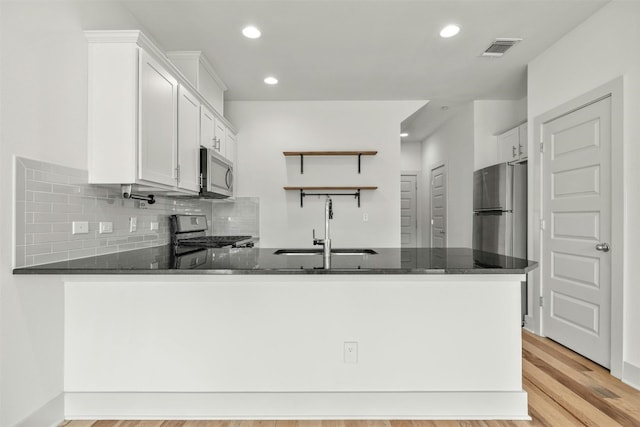 kitchen featuring kitchen peninsula, white cabinets, sink, light hardwood / wood-style floors, and stainless steel appliances