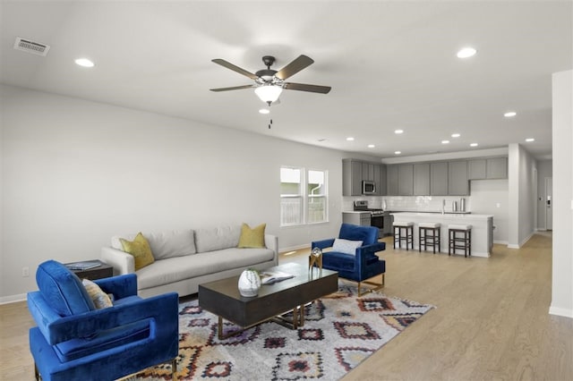 living room with light hardwood / wood-style floors, sink, and ceiling fan