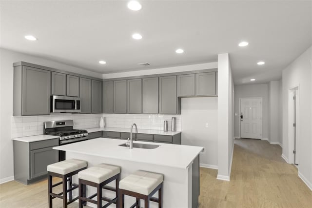 kitchen featuring sink, a kitchen island with sink, decorative backsplash, and stainless steel appliances