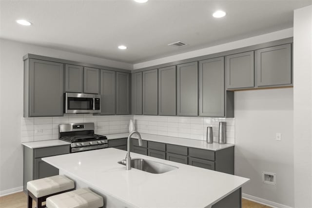 kitchen with tasteful backsplash, stainless steel appliances, and gray cabinetry