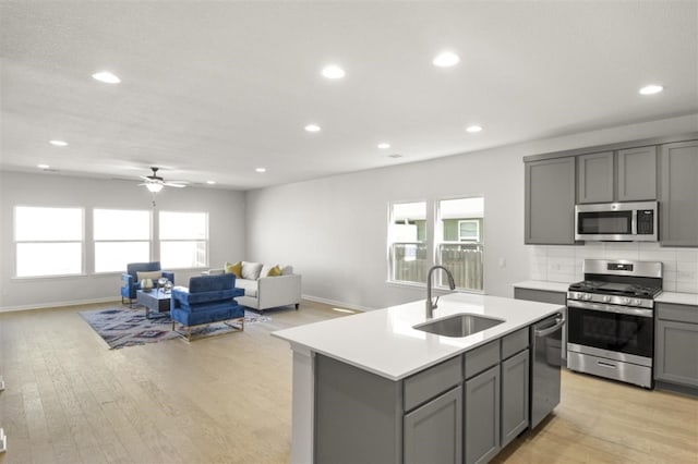 kitchen with light hardwood / wood-style flooring, an island with sink, gray cabinetry, stainless steel appliances, and sink