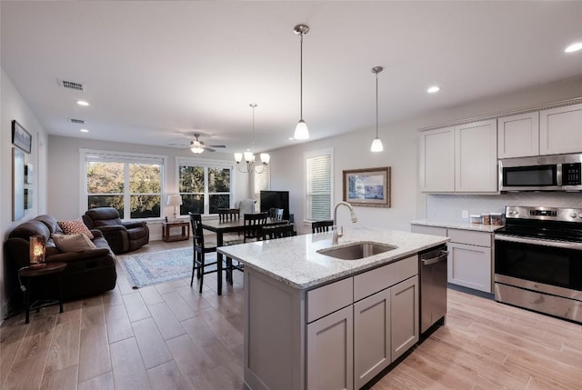 kitchen with a sink, gray cabinets, stainless steel appliances, open floor plan, and visible vents