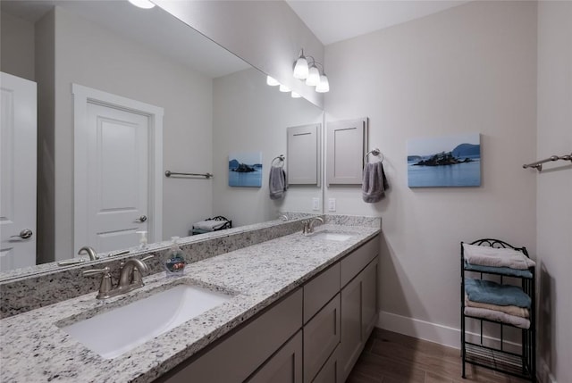 bathroom with a sink, baseboards, double vanity, and wood finished floors