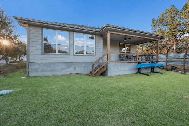 back of property with fence, stairs, ceiling fan, and a yard