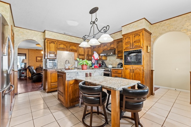 kitchen featuring a center island, a kitchen breakfast bar, stainless steel appliances, decorative light fixtures, and light tile patterned floors