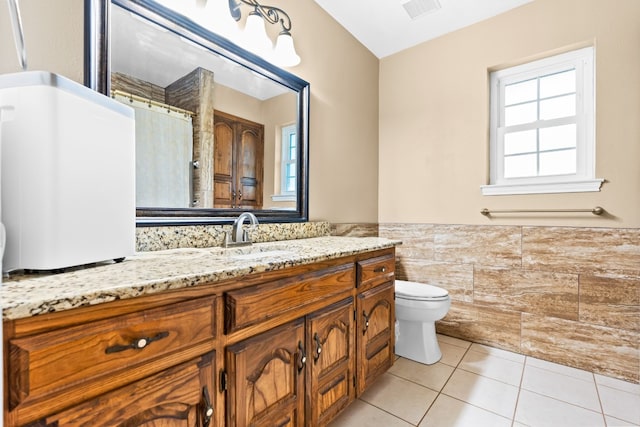 bathroom featuring toilet, tile patterned flooring, vanity, a shower with shower curtain, and tile walls