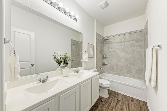 full bathroom featuring wood-type flooring, vanity, toilet, and tiled shower / bath