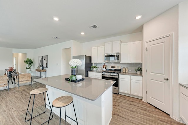 kitchen featuring white cabinets, a center island, light hardwood / wood-style floors, and appliances with stainless steel finishes