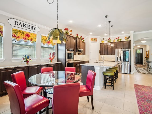 dining space with sink, light tile patterned flooring, and ornamental molding