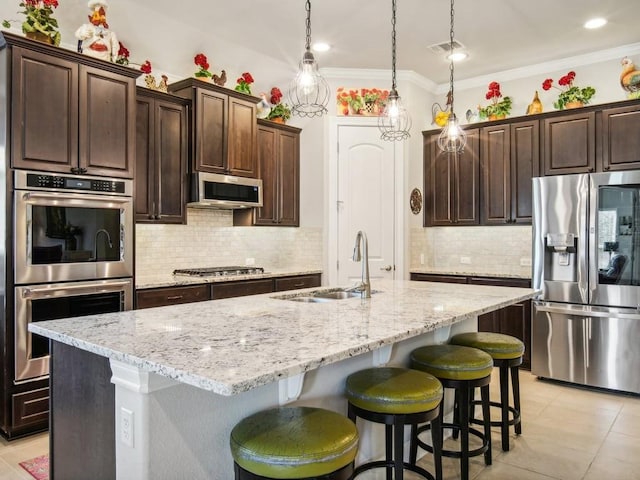 kitchen with a center island with sink, dark brown cabinetry, sink, and appliances with stainless steel finishes