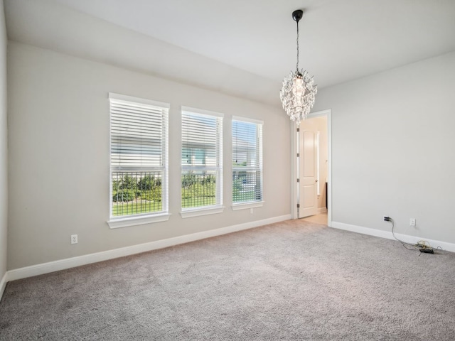 carpeted empty room featuring a notable chandelier