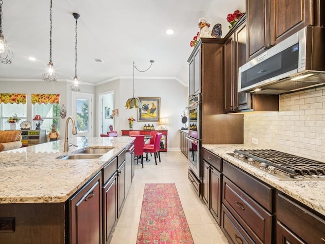 kitchen featuring sink, crown molding, decorative light fixtures, a center island with sink, and appliances with stainless steel finishes