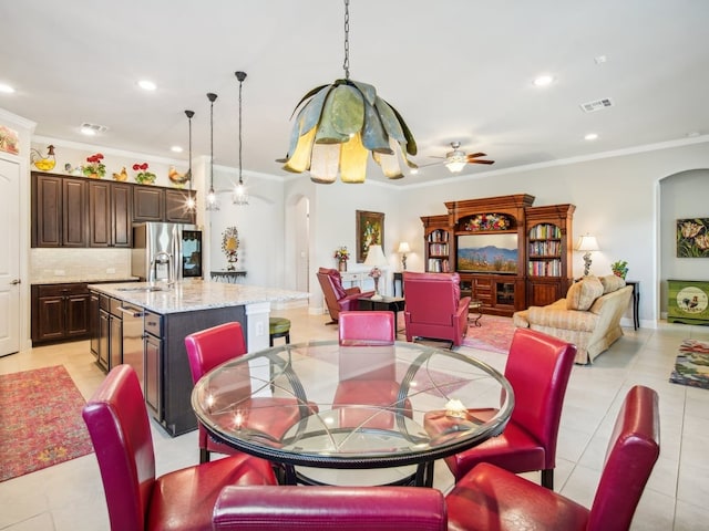 tiled dining area with ceiling fan, sink, and ornamental molding