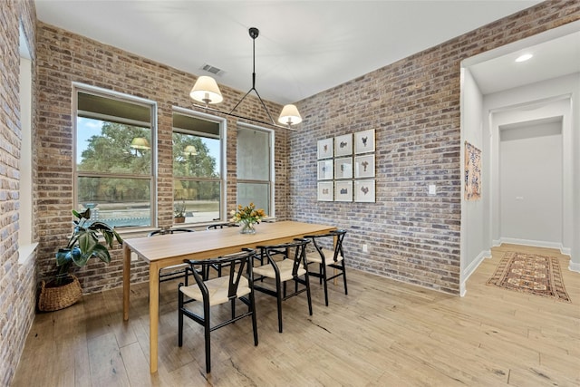 dining room with brick wall and light wood-type flooring