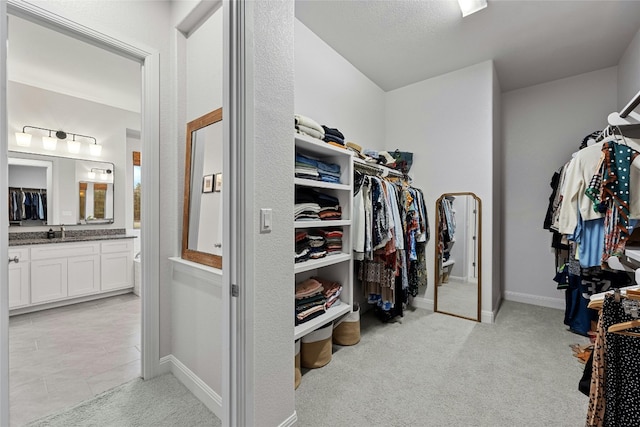 walk in closet with sink and light carpet