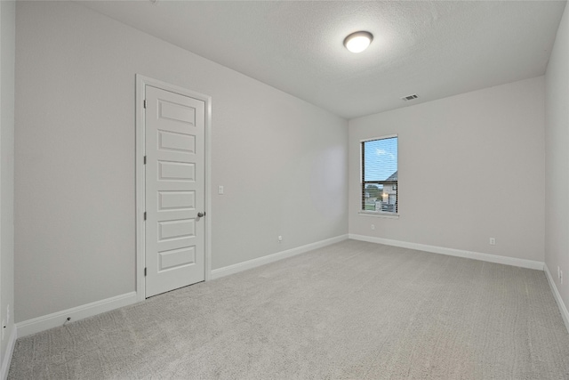 carpeted empty room featuring a textured ceiling