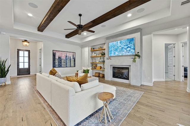 living room with ceiling fan, beamed ceiling, and light hardwood / wood-style flooring