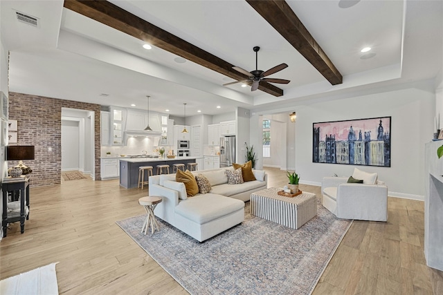 living room featuring light hardwood / wood-style floors, beamed ceiling, and ceiling fan