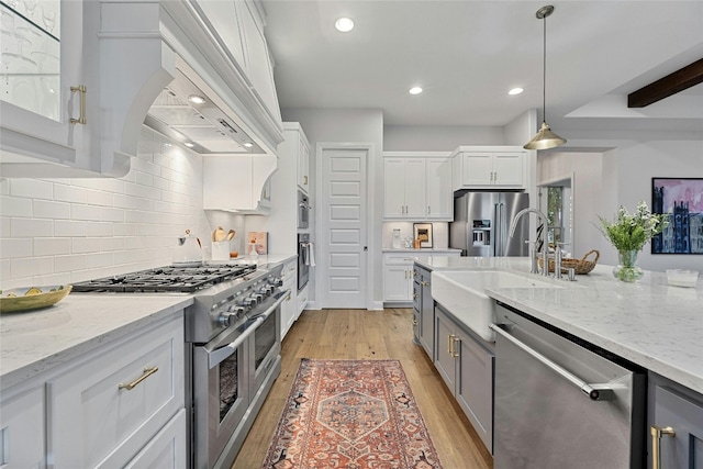 kitchen featuring high quality appliances, light hardwood / wood-style flooring, pendant lighting, custom exhaust hood, and white cabinetry