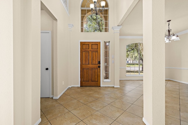 tiled foyer entrance with ornamental molding, a chandelier, and a high ceiling