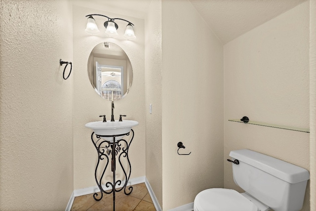 bathroom featuring toilet, sink, vaulted ceiling, and tile patterned flooring