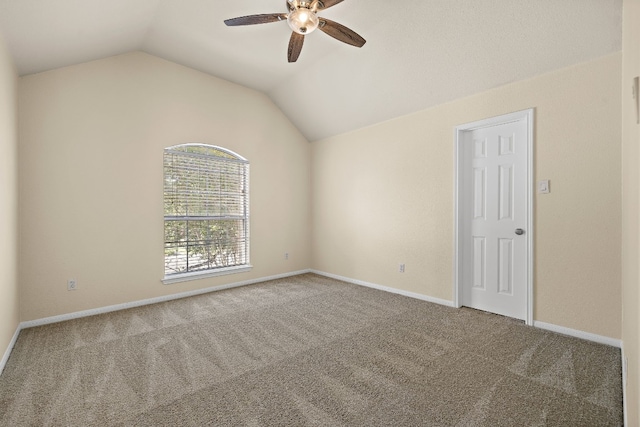 carpeted spare room with ceiling fan and vaulted ceiling