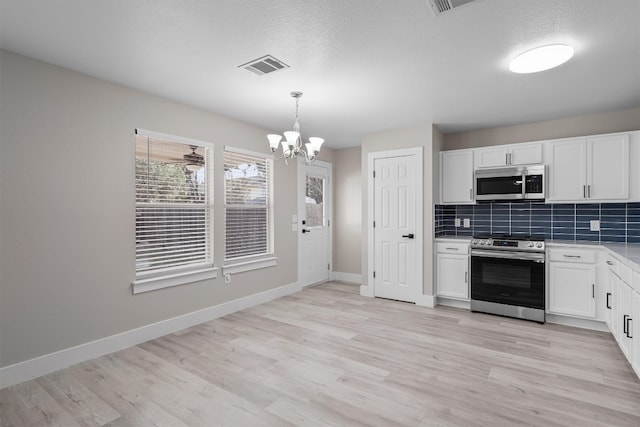 kitchen featuring white cabinets, hanging light fixtures, an inviting chandelier, light hardwood / wood-style flooring, and stainless steel appliances