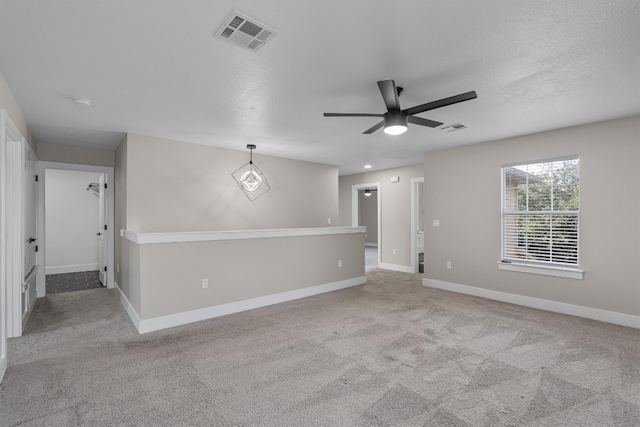 empty room featuring light carpet, a textured ceiling, and ceiling fan