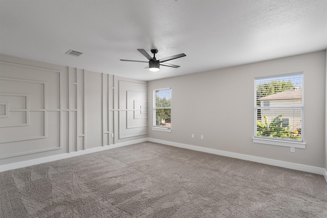 empty room with a textured ceiling, a wealth of natural light, and carpet floors