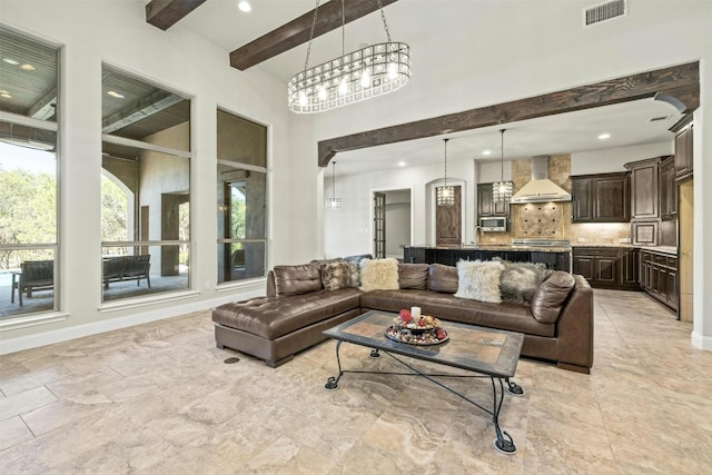 living room featuring beam ceiling, a towering ceiling, visible vents, and baseboards