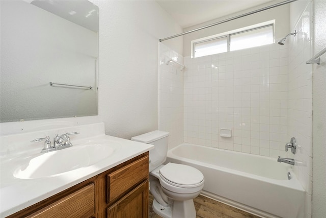 full bathroom with tiled shower / bath, vanity, hardwood / wood-style floors, and toilet