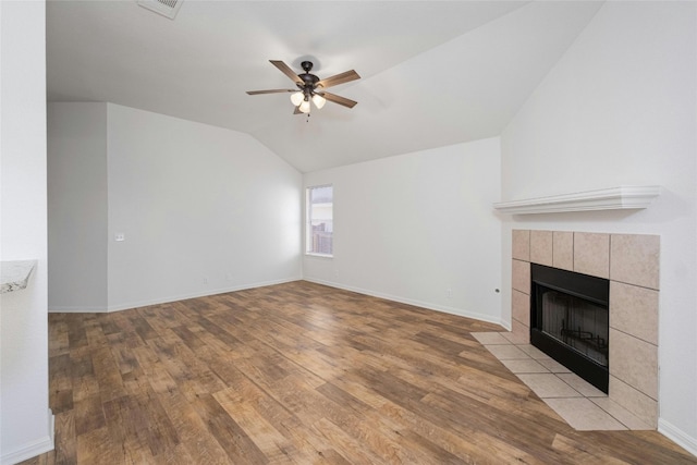 unfurnished living room with ceiling fan, lofted ceiling, light wood-type flooring, and a tile fireplace