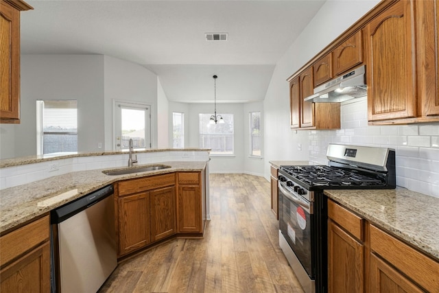 kitchen featuring an inviting chandelier, light wood-type flooring, vaulted ceiling, sink, and stainless steel appliances