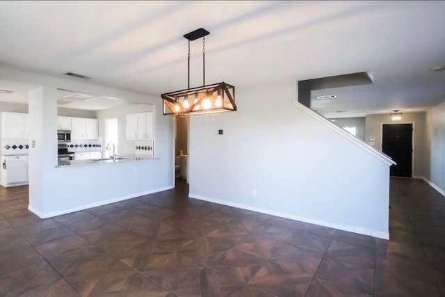 kitchen with kitchen peninsula, stainless steel appliances, sink, decorative light fixtures, and white cabinets