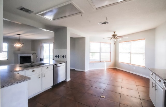 kitchen featuring a healthy amount of sunlight, hanging light fixtures, white cabinetry, stainless steel dishwasher, and sink