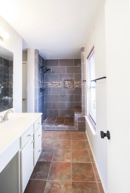 bathroom with a tile shower and vanity