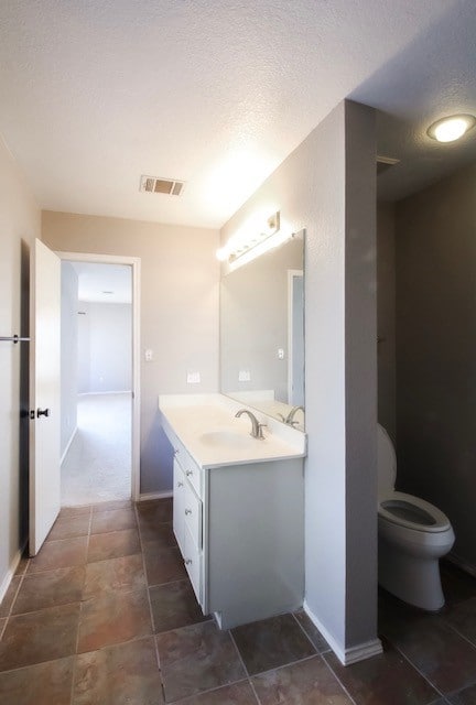 bathroom featuring toilet, vanity, and a textured ceiling