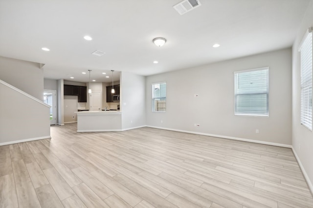 unfurnished living room with a wealth of natural light and light wood-type flooring