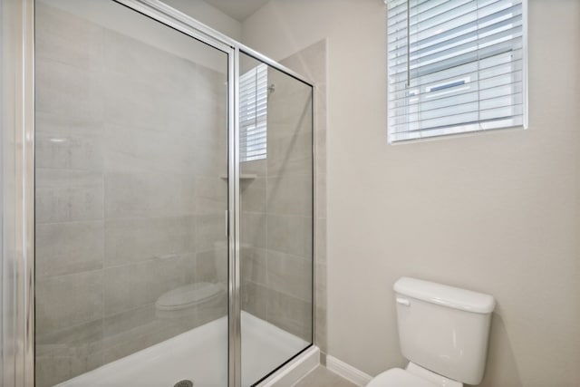 bathroom with a shower with door and toilet