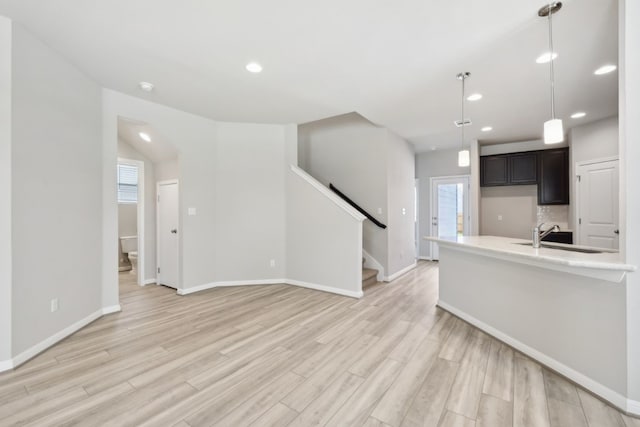 kitchen with light hardwood / wood-style floors, sink, backsplash, and hanging light fixtures