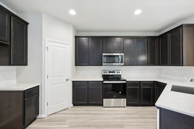 kitchen featuring light hardwood / wood-style floors, dark brown cabinetry, stainless steel appliances, and sink