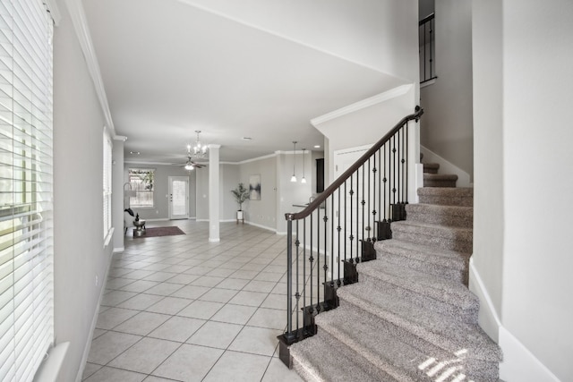 stairway with crown molding, tile patterned floors, a chandelier, and plenty of natural light