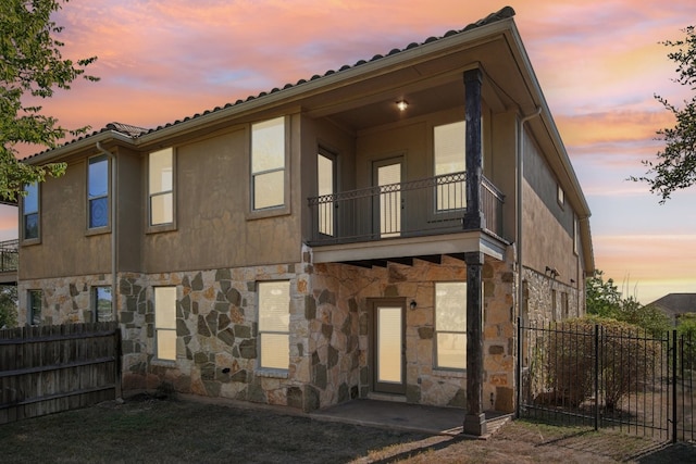 back house at dusk featuring a balcony